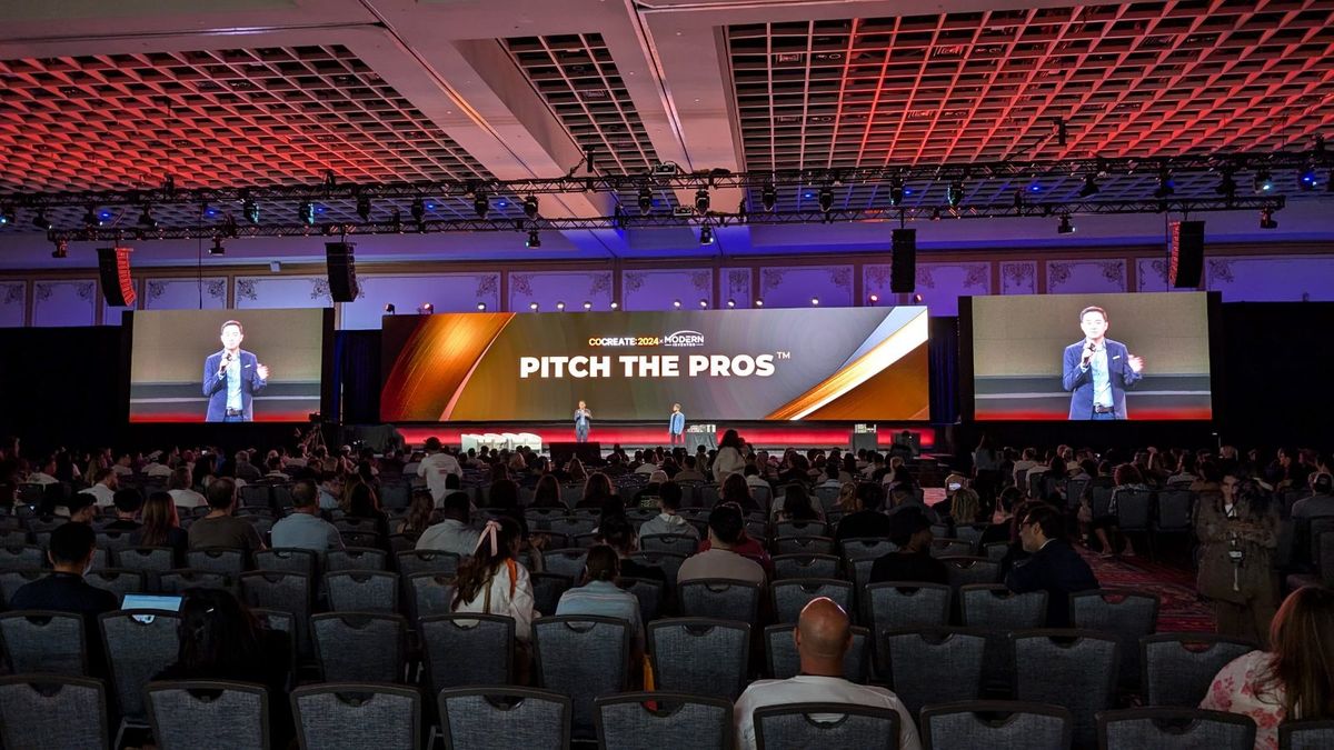 The Pitch the Pros stage at CoCreate — three LED screens over a full ballroom