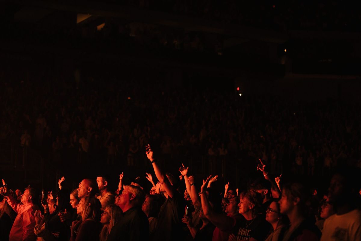 Arena crowd with hands raised in low light