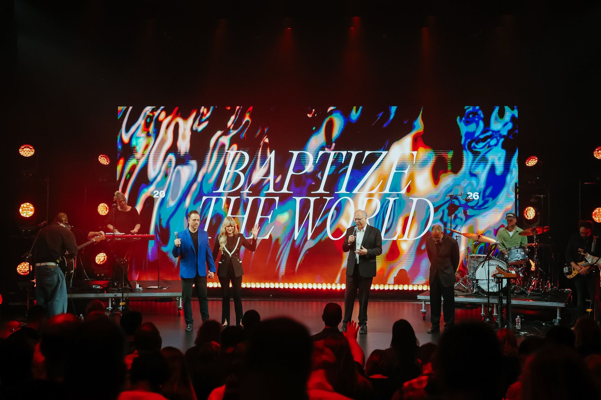 The band and hosts across the stage in front of the full-width GP2 wall