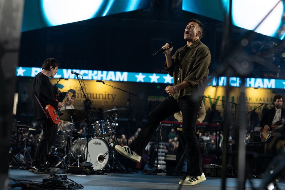 Phil Wickham mid-jump in front of the LED ribbon at the UCCU Center, Utah Valley 2025