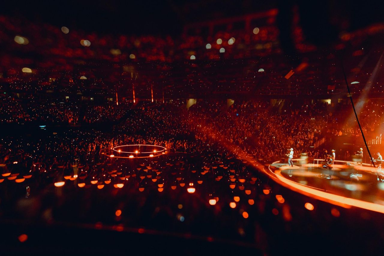 Wide across a full arena lit by phone lights
