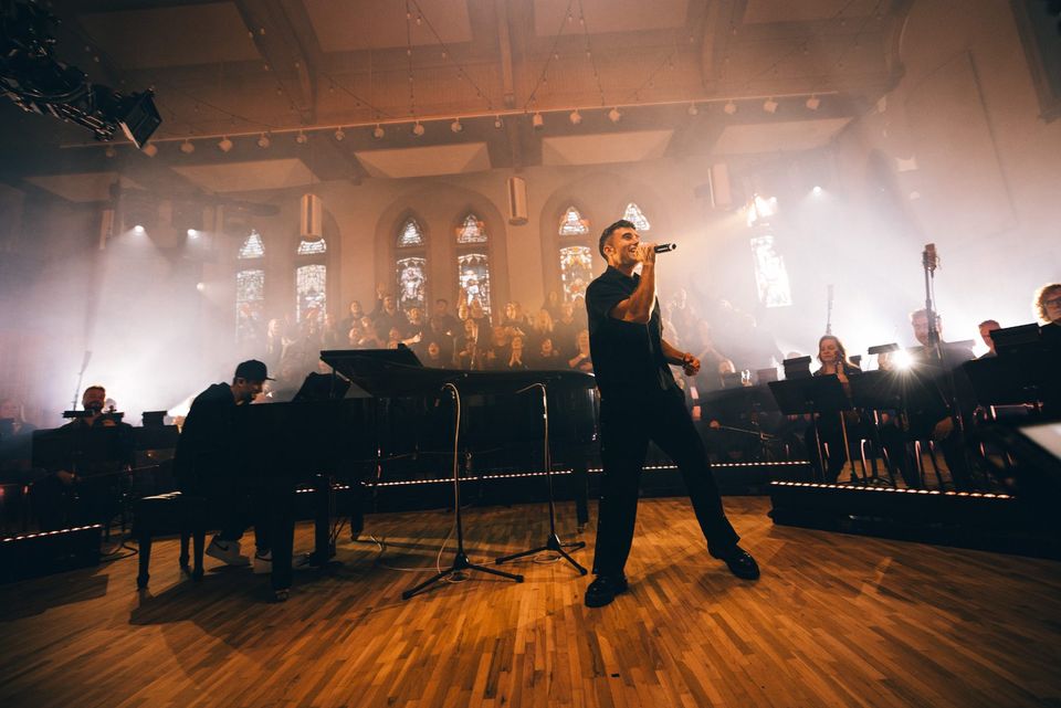 Singer in a chapel with stained glass during a Tommee Profitt live recording