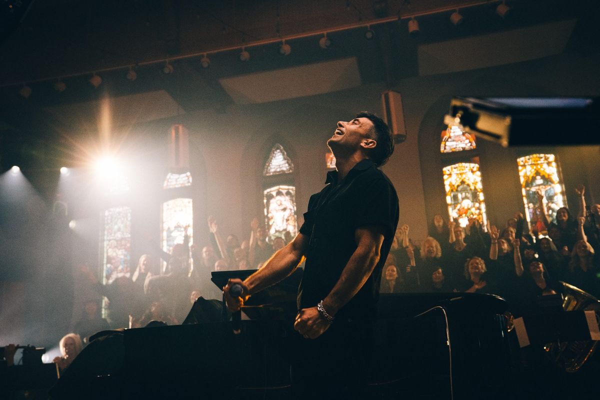 Singer under a single light beside stained glass