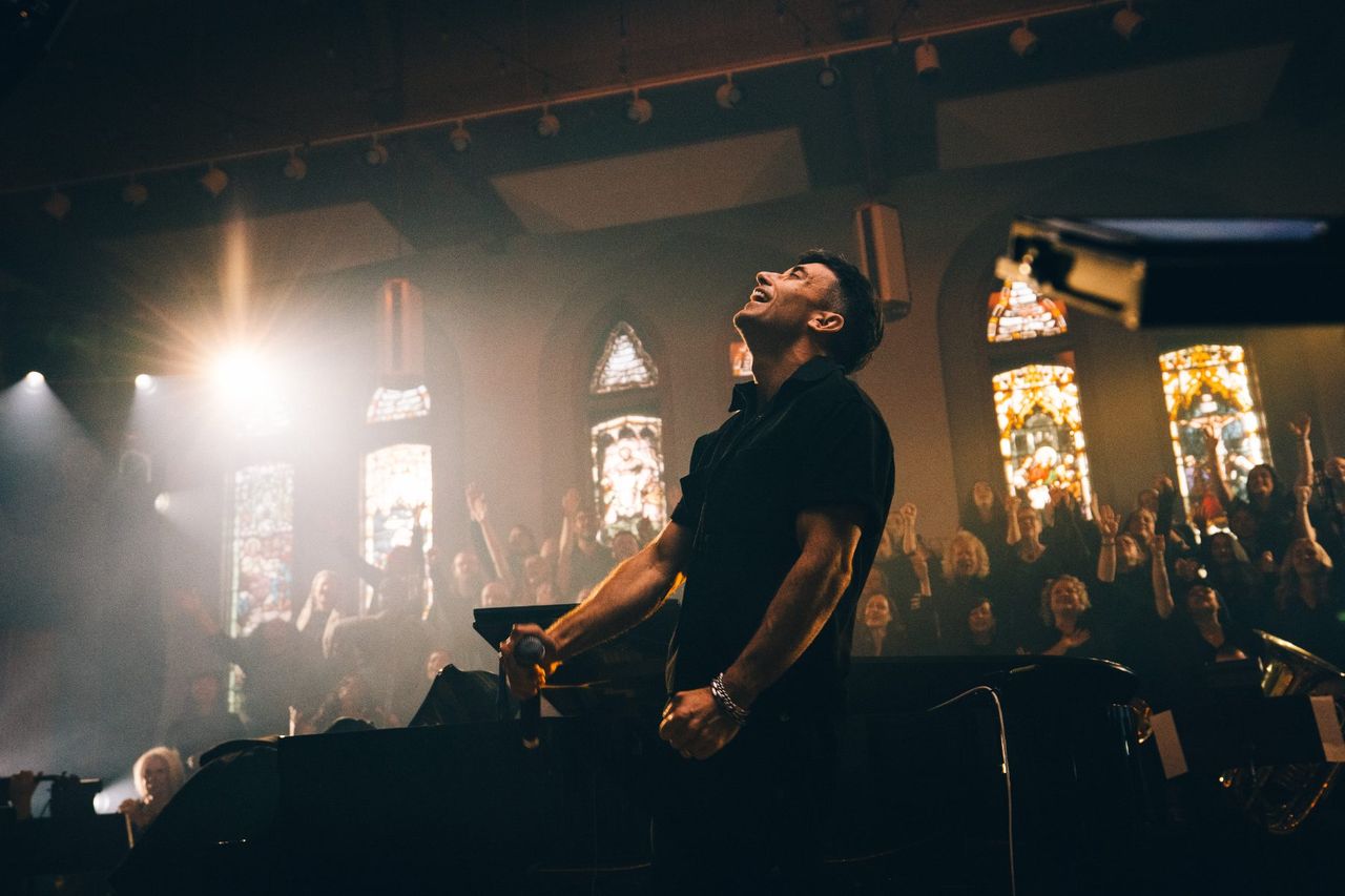 Singer under a single light beside stained glass